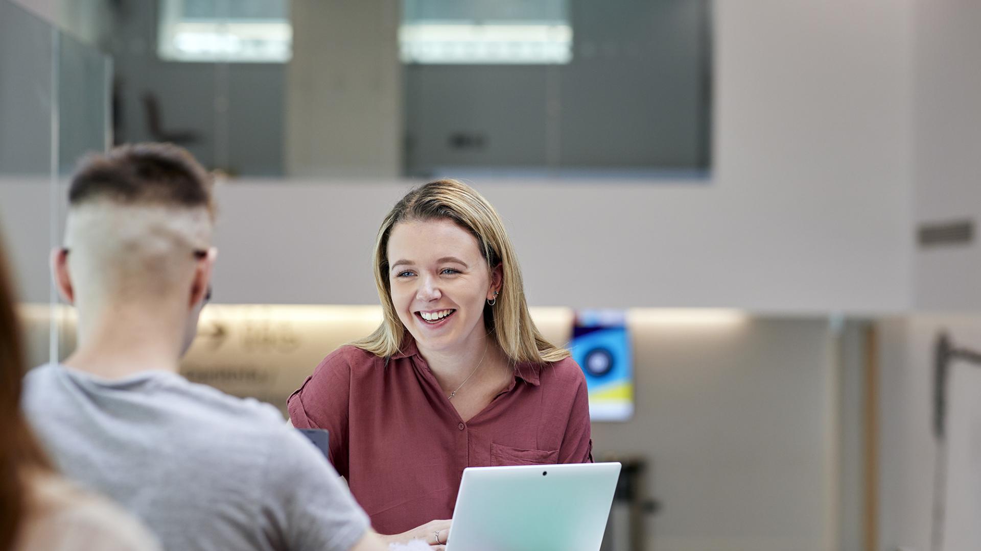 two students chatting, laptop on the table