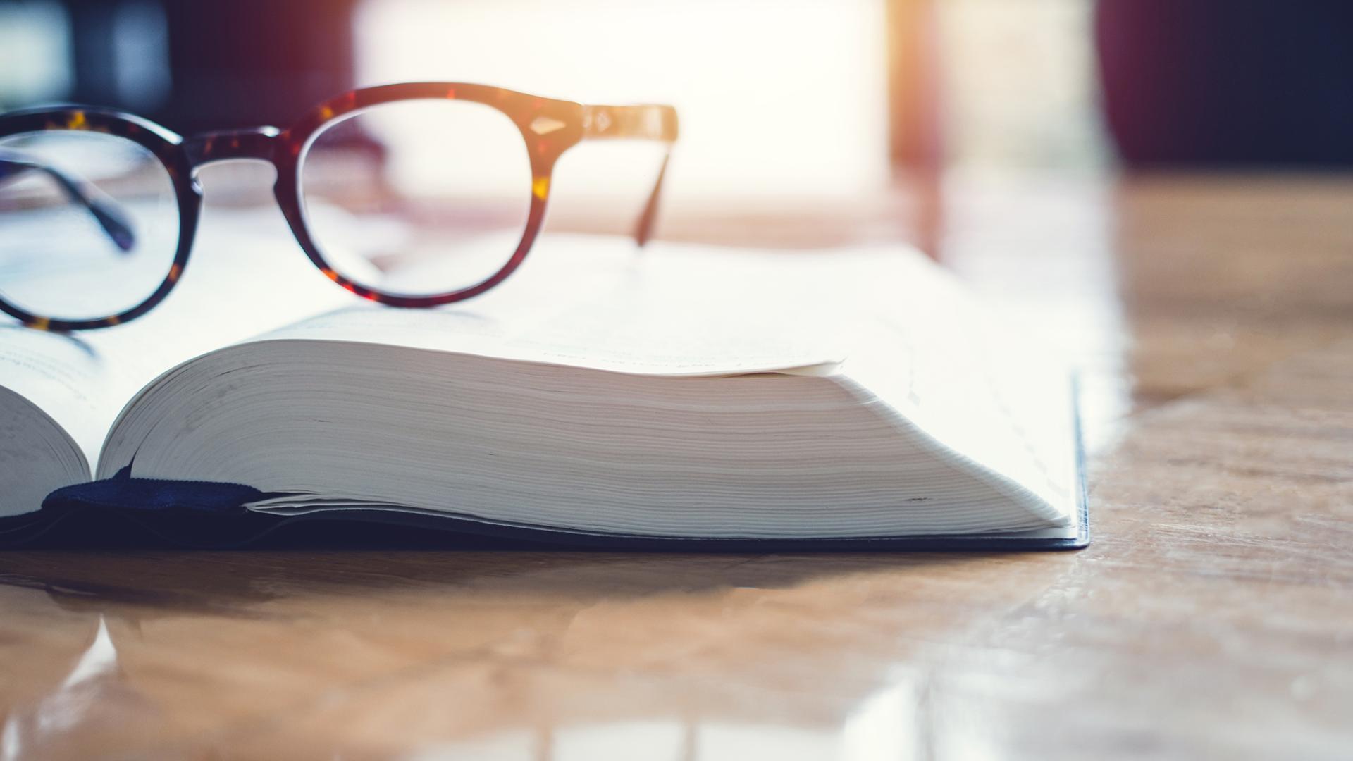 A pair of glasses resting on an open book