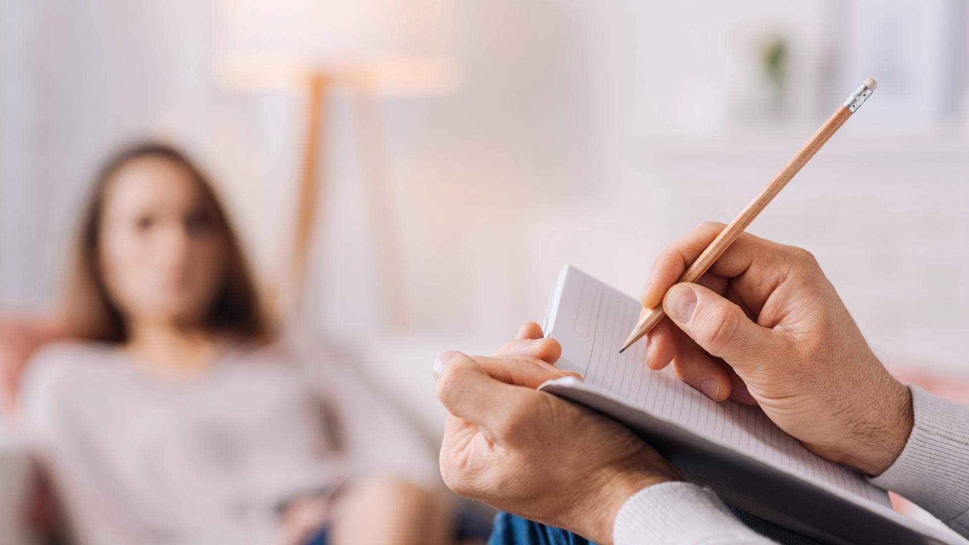 Therapy Session - Therapist interviewing young girl whilst taking notes in a notepad