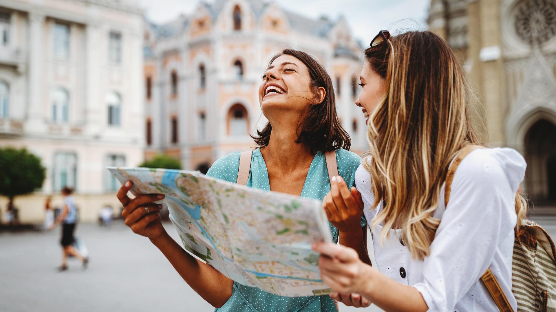 Tourist girls exploring an old town laughing over a map