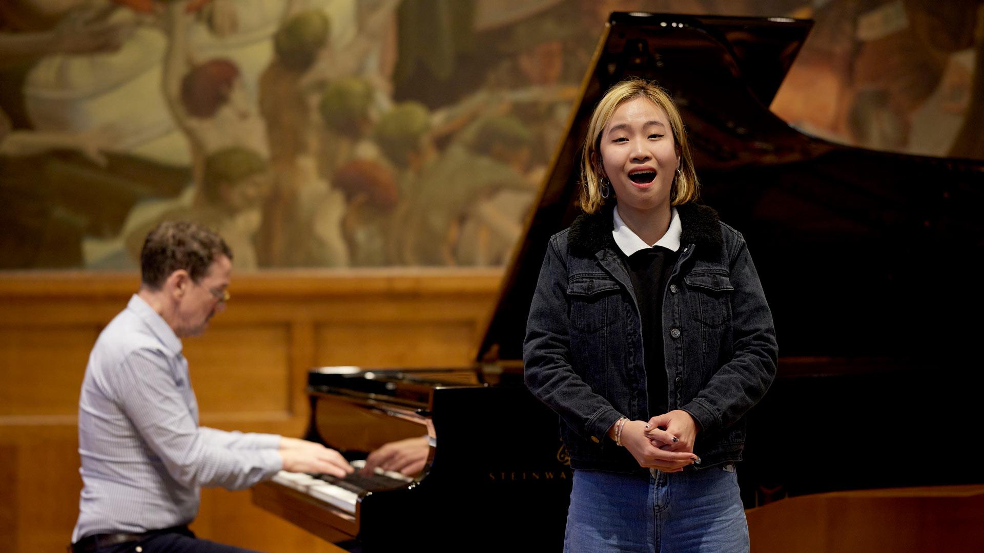 Cantores yn perfformio gyda person yn cyfeilio ar y biano