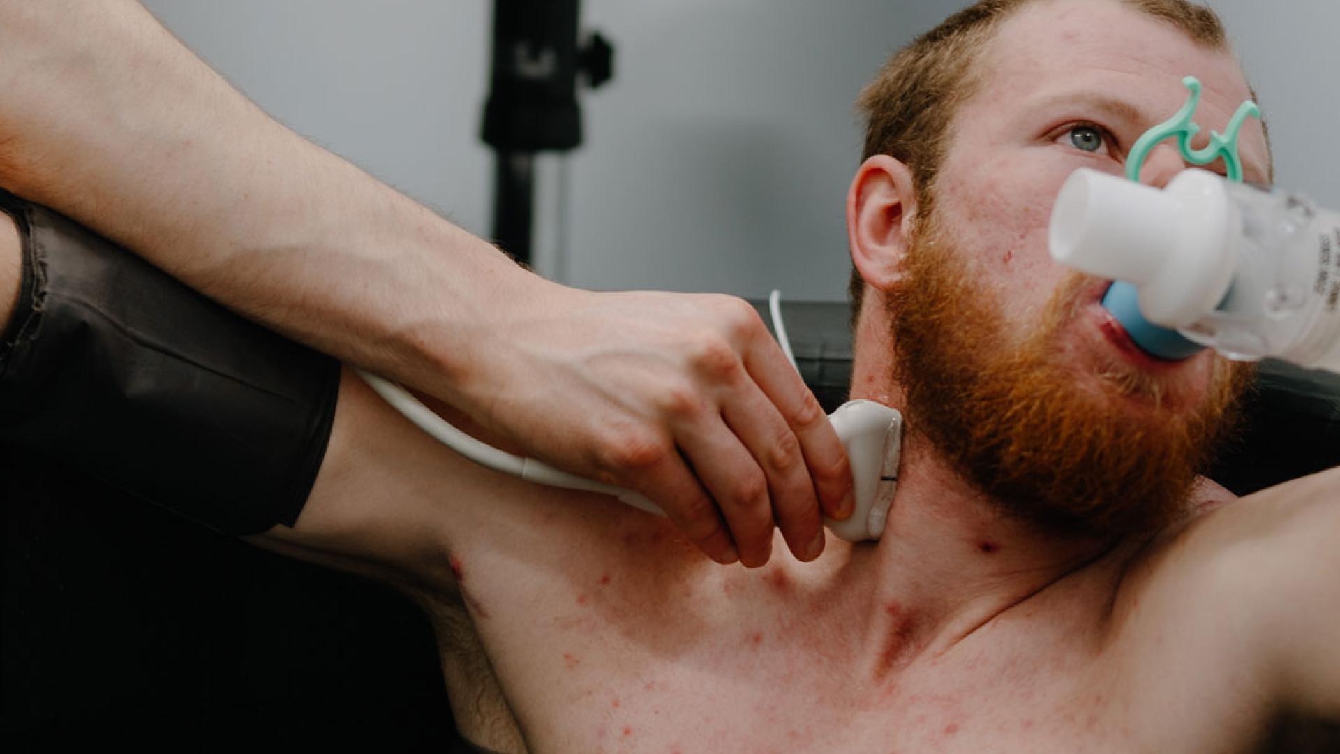 Instructor checking heart rate of a student in a water immersion bath with breathing aparatus