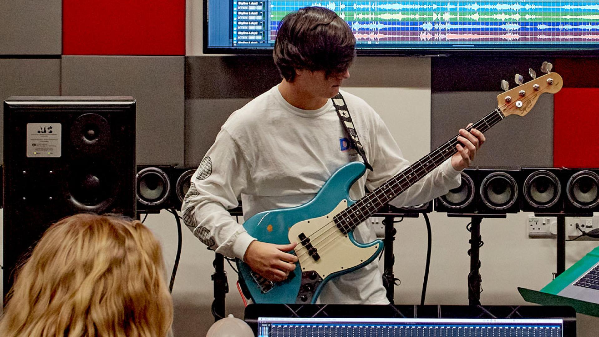 musician playing bass guitar in university studio