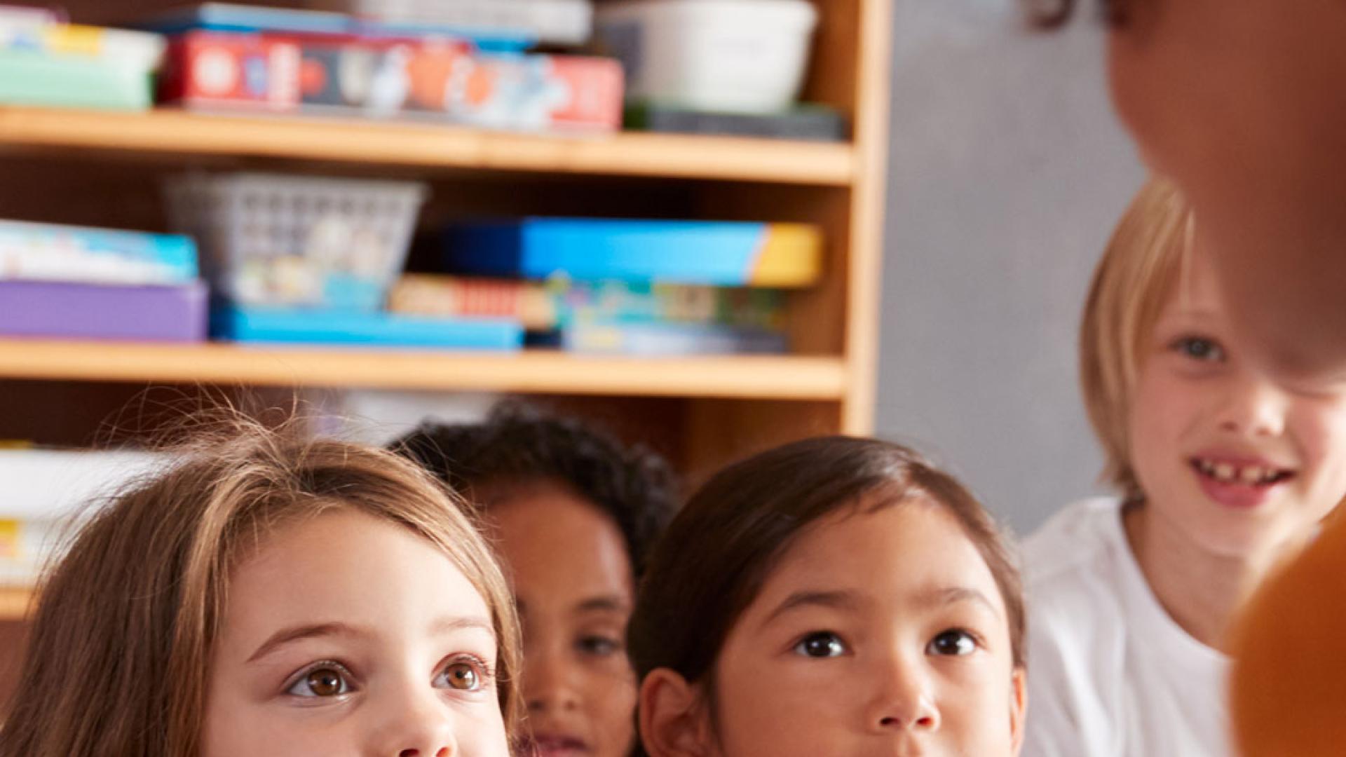 Group of primary school children sat listening to teacher