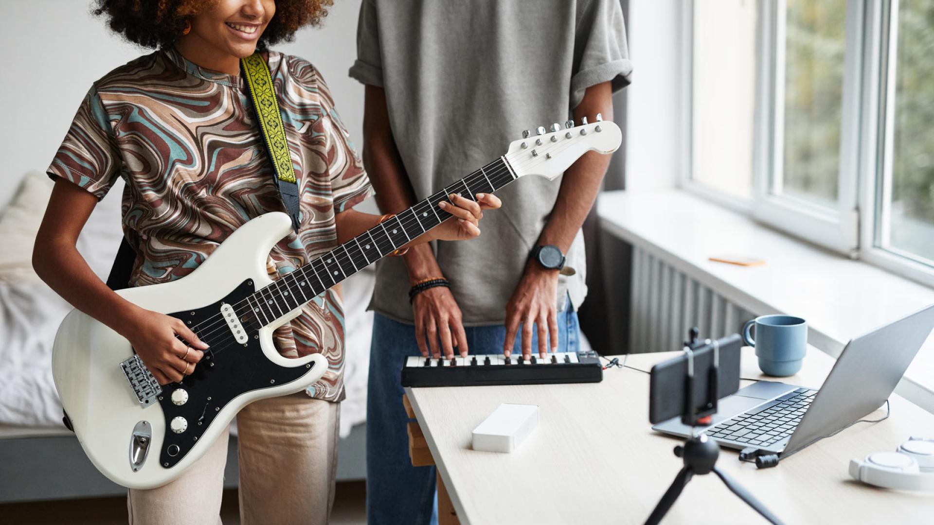 Music & Media Studies students recording instruments whilst recording and filming themselves on a computer