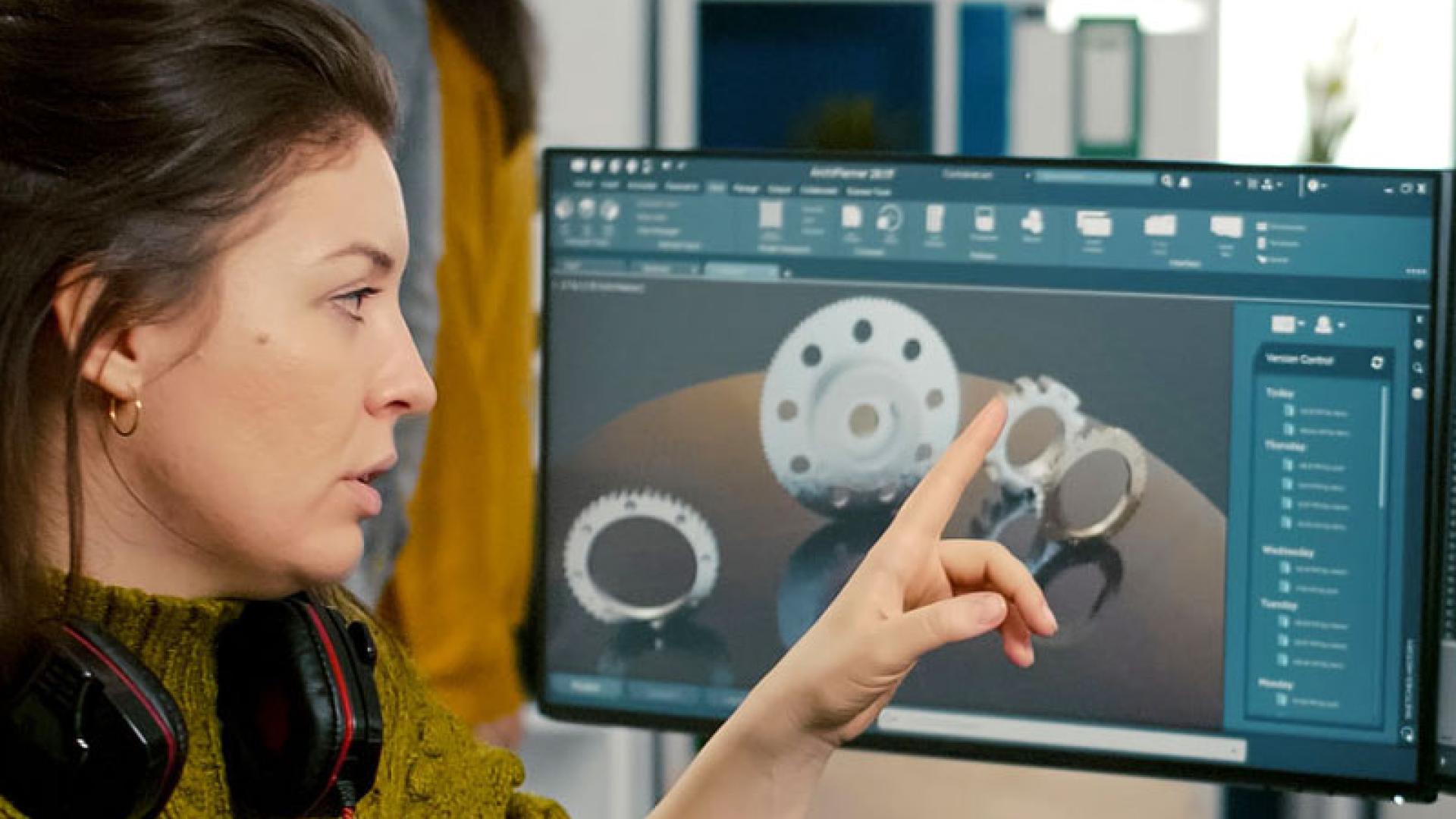 Game design student and lecturer talking around computer screen displaying 