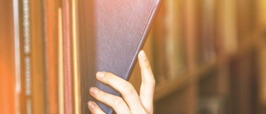 Student taking a book off a shelf.