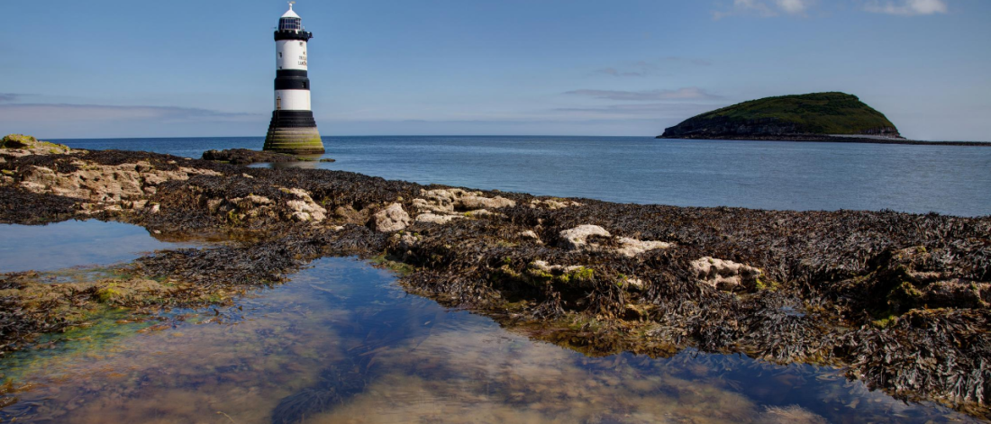 Image of a light house, island, sea and blue sky.