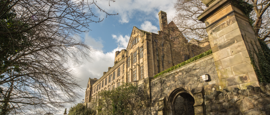 Bangor University - Main Arts Building with trees and blue sky.