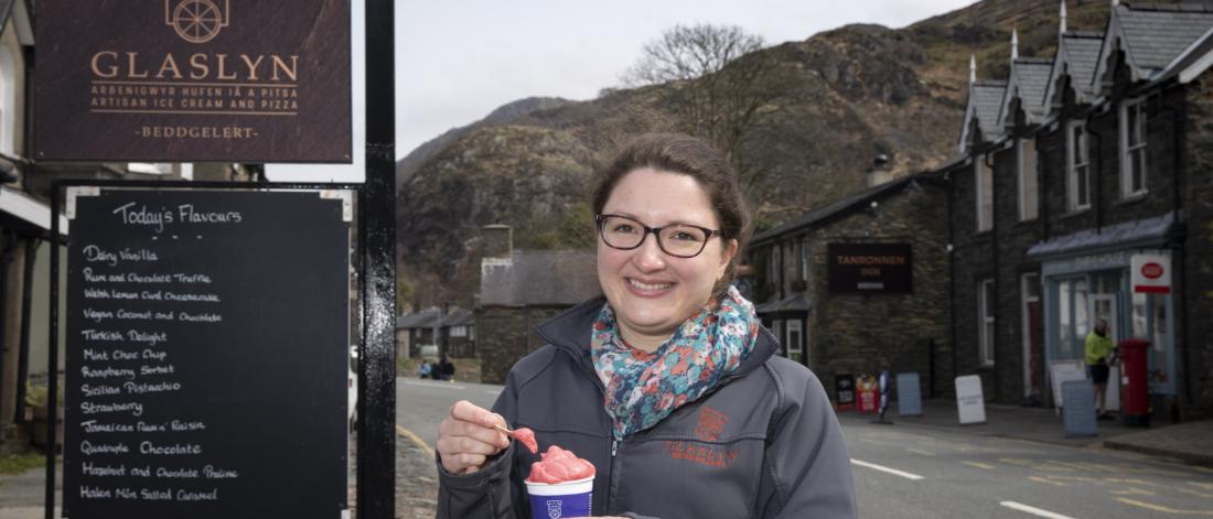 Young woman eats ice cream outside Glaslyn Ices, Bbeddgelert