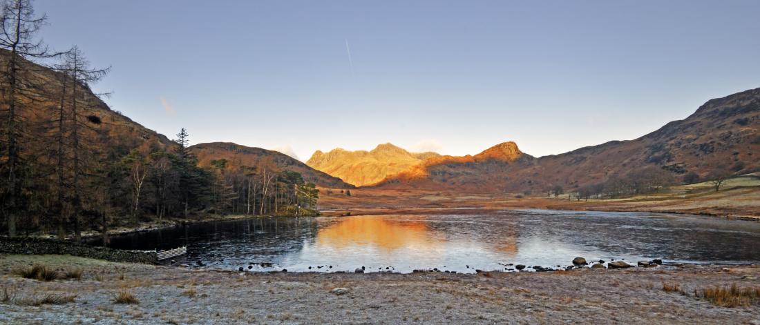 A frozen lake with sunlight on a far mountain