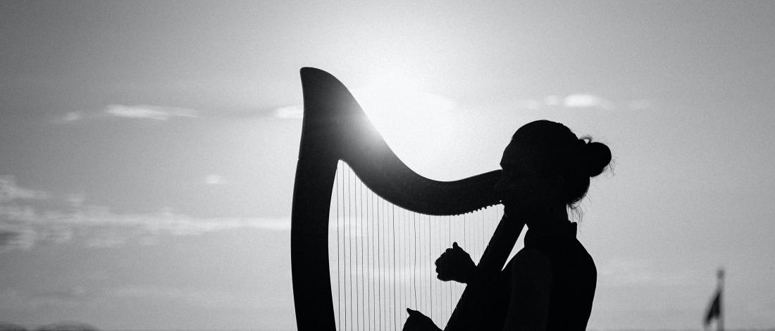 Black and white photo of a woman playing a harp outside