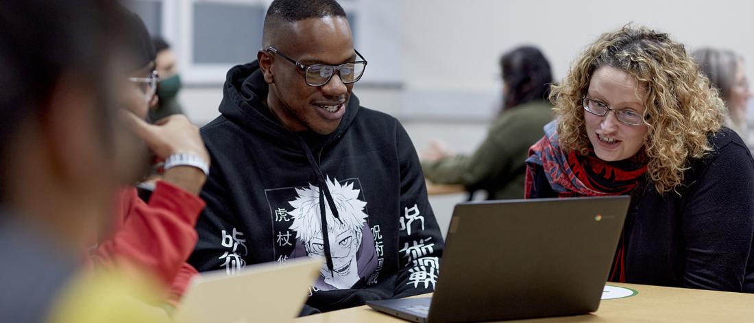 Students sitting at a desk with a laptop