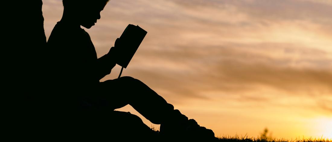 A child reading a book outside