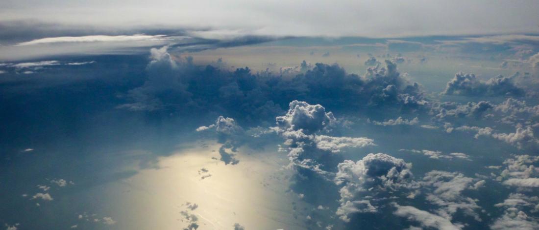 Aerial view looking down at clouds over the sea with sunlight reflected from below
