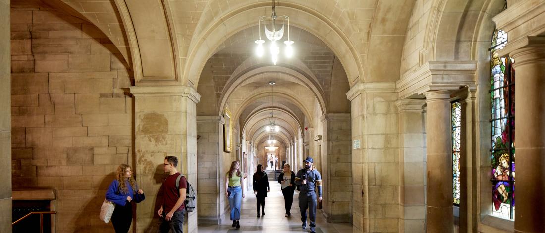 A group of students walking down the main corridor at the Main Arts building