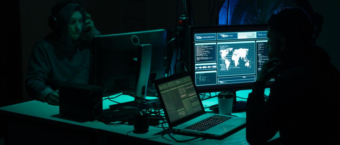 Two people sitting in front of computer screens in a dark room