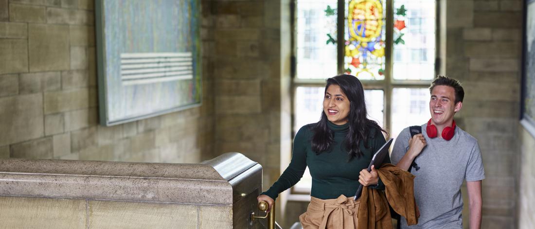 Two students walking up the stairs in Bangor University's Main Arts building