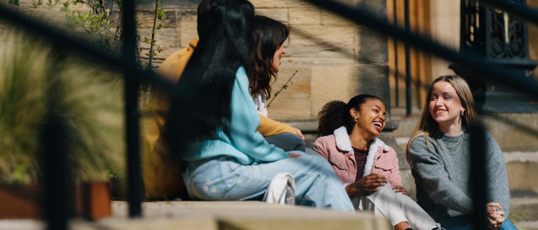 Group of students sitting on some steps talking 