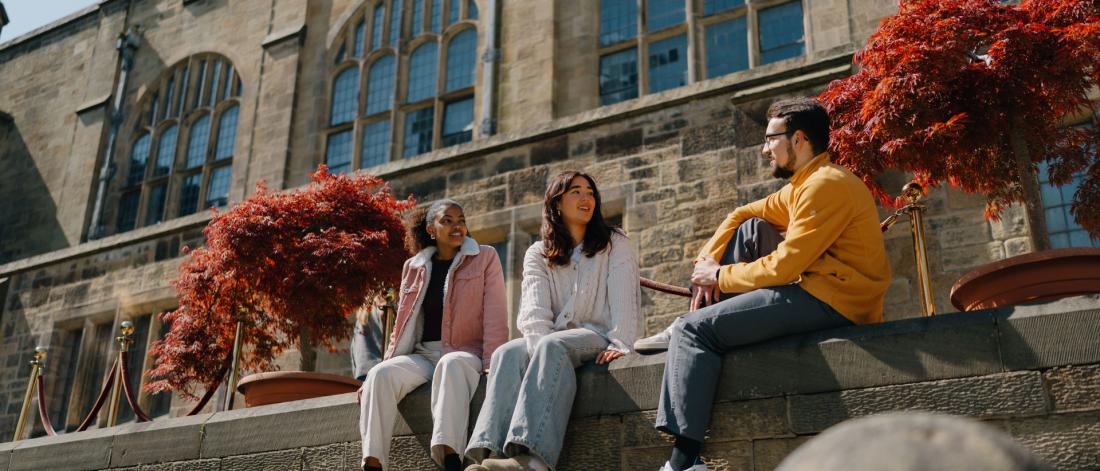 Group of students talking sitting in the inner quad of the Main University Building