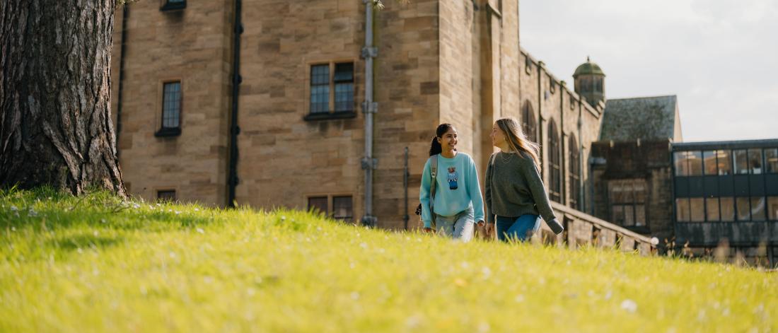 Two students walking in front of main arts university building