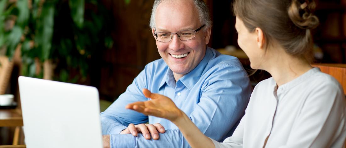 Man and woman sitting at computer talking and smiling