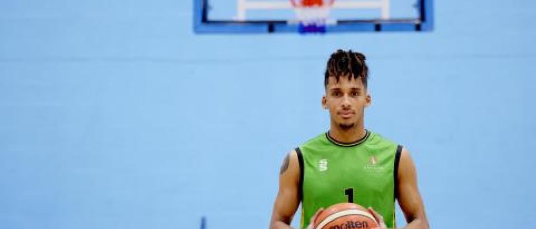 A Bangor University Basketball player holding a basket ball 