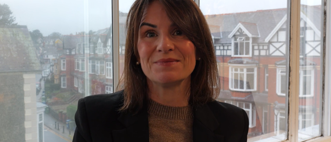 Llun o Dr Sara Parry gyda dinas Bangor yn y cefndir