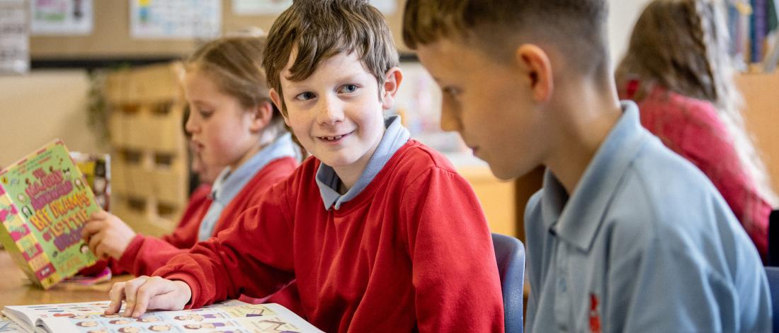 Three school children reading in a classroom