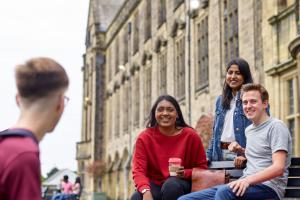 A group of students socialising on a bench on the terrace of the Main Arts building