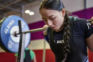 Female student lifting weights using the facilities at the University's Canolfan Brailsford