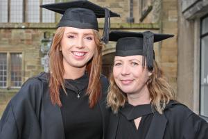 A couple of students in their cap and gowns outside the Main Arts building