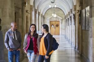 three students chatting in the corridor at the historic Main Arts building 