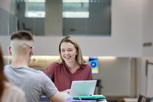 two students chatting, laptop on the table