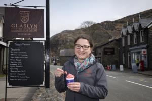 Young woman eats ice cream outside Glaslyn Ices, Bbeddgelert