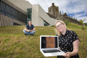 Person holding a laptop with university in the background