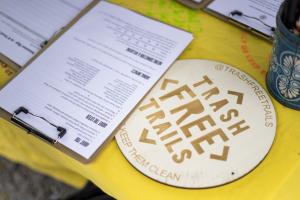 A desk with a  sign-up sheet and Trash Free Trails logo  as stencilled words