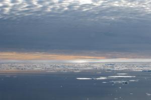 Arctic sea with a glow on the horizon and patches of sea ice