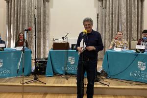 Bangor University 3rd degree Quiz members sit behind tables and microphones ready to compete. In the front is producer, David Tyler.