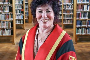 Comedian Ruby Wax in a red academic gownat Bangor Universoty library