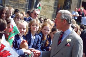   Tywysog Siarl yn siarad efo plant sygol sy'n cwifio'r Ddraig Goch, yn ystod ymweliad â Phrifysgol bangor yn 2009