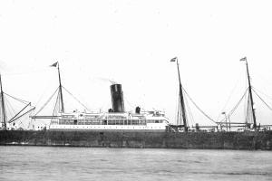 A black and white image of a steamship fills the frame she has four short masts and a funnel at the centre.