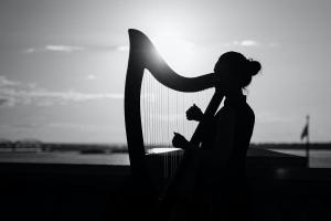 Black and white photo of a woman playing a harp outside