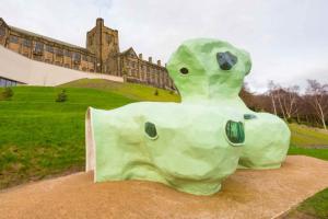 Green fibreglass structure with main university building in the background