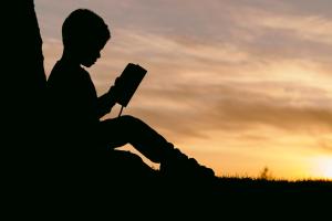 A child reading a book outside