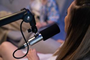 Image showing the back of someone's head, sitting in front of a microphone recording 