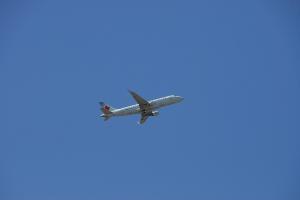 A passenger aeroplane appears quite small against a blue sky