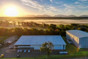 Aria Flm Studios in the foreground with a sunrise over a pastoral setting and mountains in the background