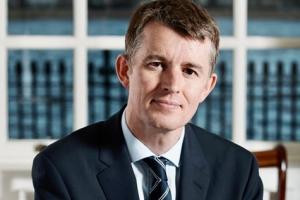 person with short hair in a business suit sitting down