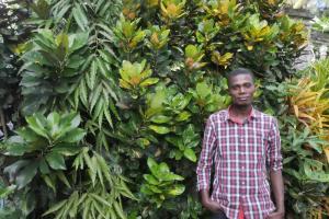 Member of Dahari staff, Samirou Soulaimana, standing in front of greenery